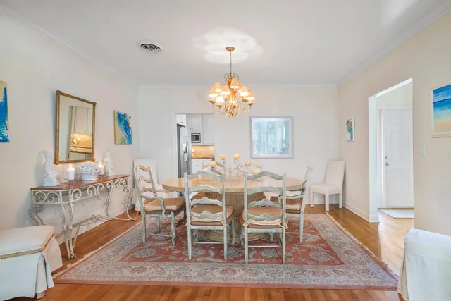 a dining room with wooden floor a chandelier a wooden table and chairs