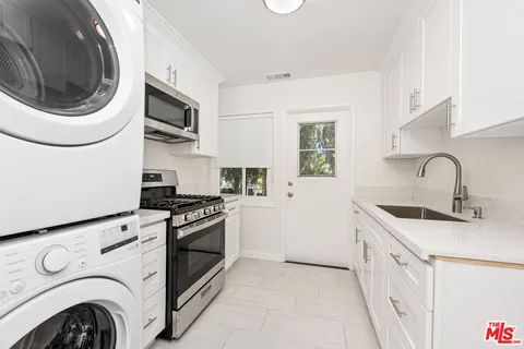 a kitchen with stainless steel appliances granite countertop white cabinets a sink and a stove