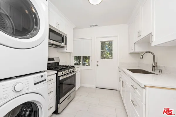 a kitchen with stainless steel appliances granite countertop white cabinets a sink and a stove