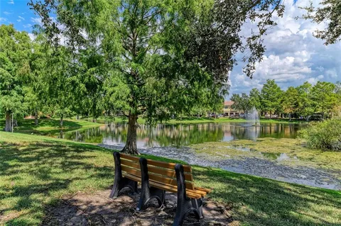 a view of a lake with a bench and trees in the background