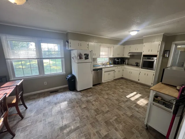 a kitchen with a dining table chairs and refrigerator