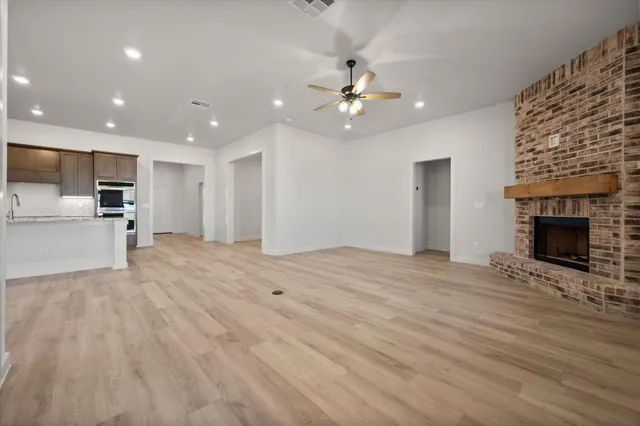a view of an empty room with kitchen and a fireplace