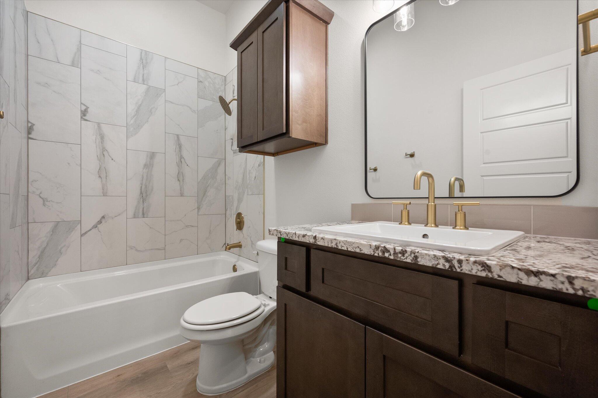 7010 16th Street Lubbock, TX 79416 - Photo 22 of 28 a bathroom with a granite countertop sink toilet and shower