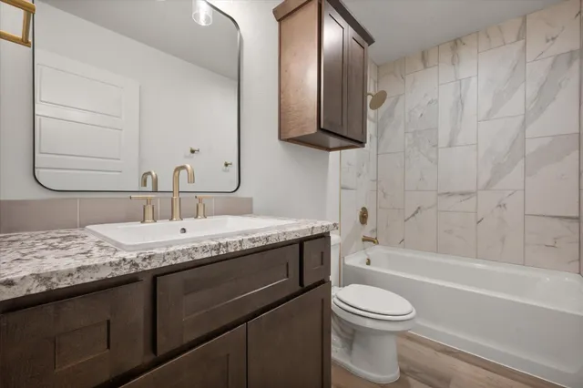 a bathroom with a granite countertop sink toilet and shower