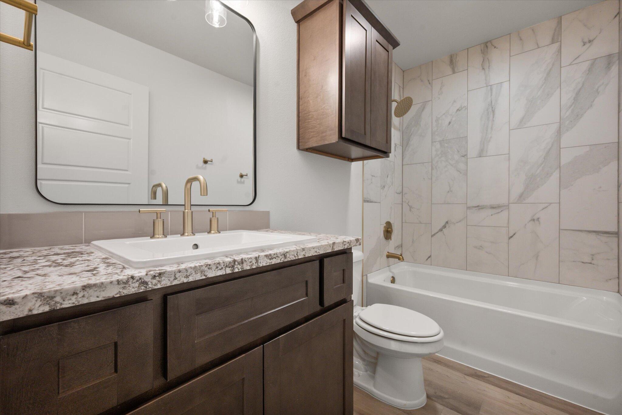 7010 16th Street Lubbock, TX 79416 - Photo 25 of 28 a bathroom with a granite countertop sink toilet and shower