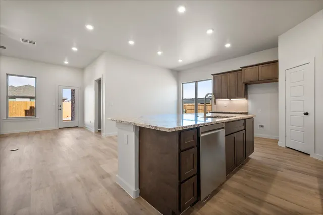 a large kitchen with stainless steel appliances a large counter top and wooden floors