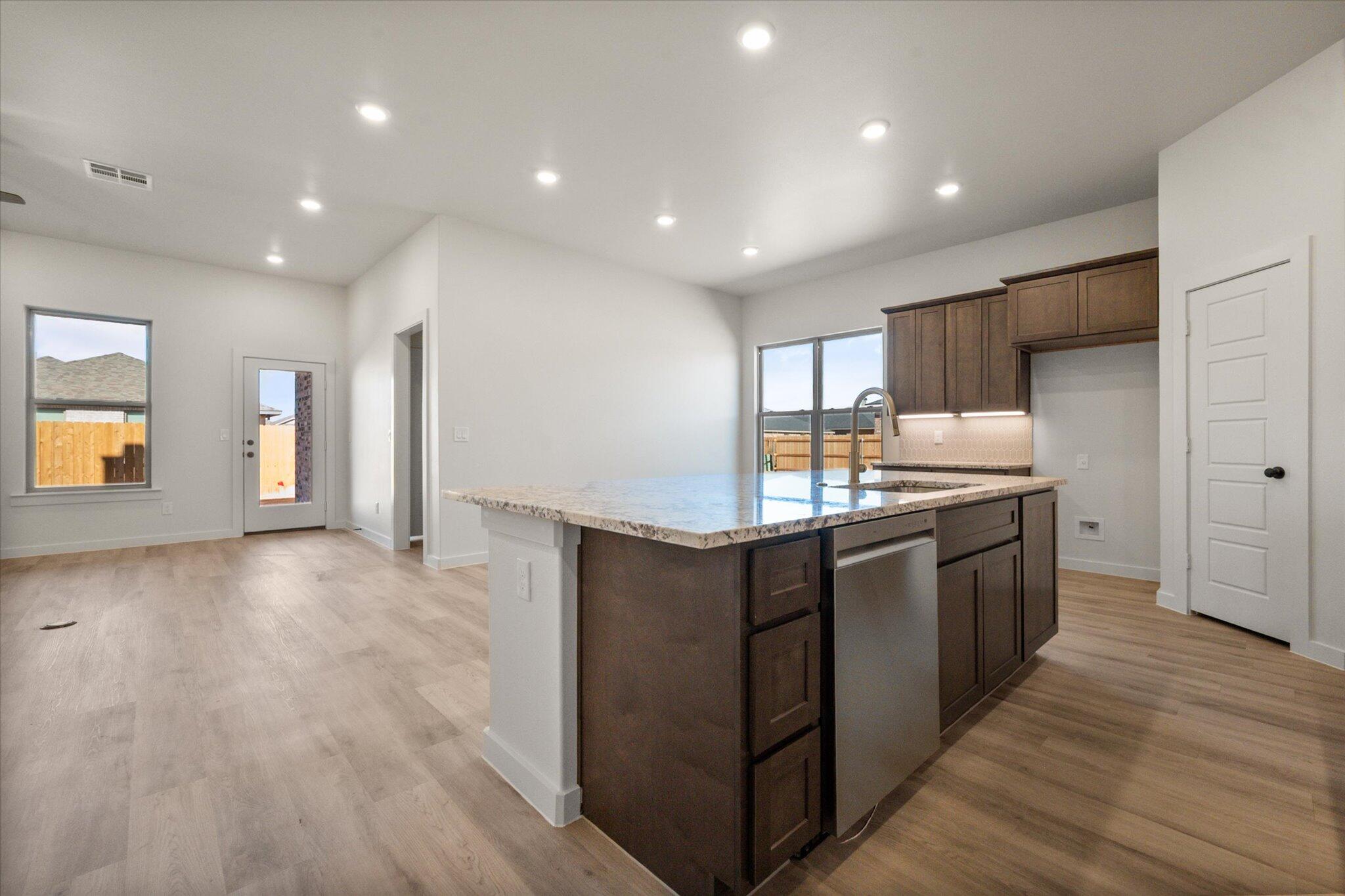 7010 16th Street Lubbock, TX 79416 - Photo 3 of 28 a large kitchen with stainless steel appliances a large counter top and wooden floors