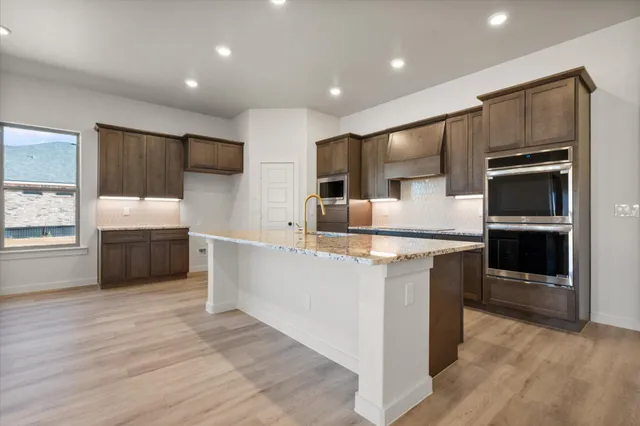 a large kitchen with stainless steel appliances a stove a sink and a refrigerator