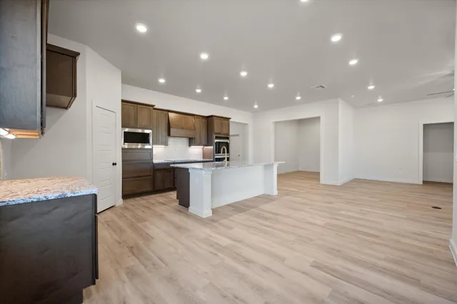 a large kitchen with stainless steel appliances kitchen island a large counter top and a stove top oven