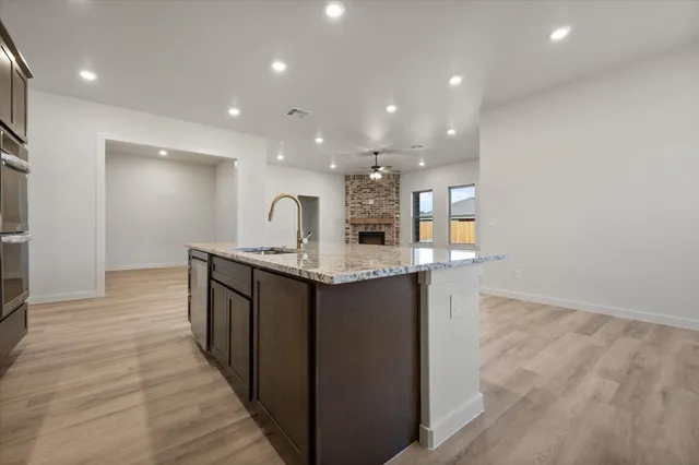 a open kitchen with kitchen island a sink dishwasher a stove and a refrigerator with wooden floor