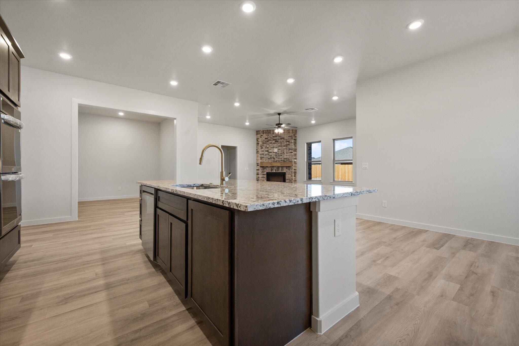 7010 16th Street Lubbock, TX 79416 - Photo 8 of 28 a open kitchen with kitchen island a sink dishwasher a stove and a refrigerator with wooden floor