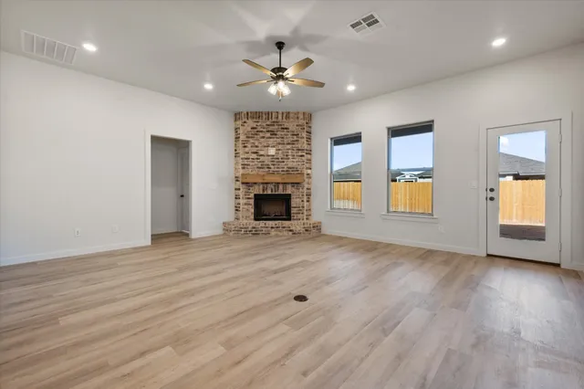 an empty room with wooden floor fireplace and window