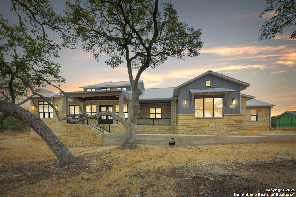 a front view of a house with large trees