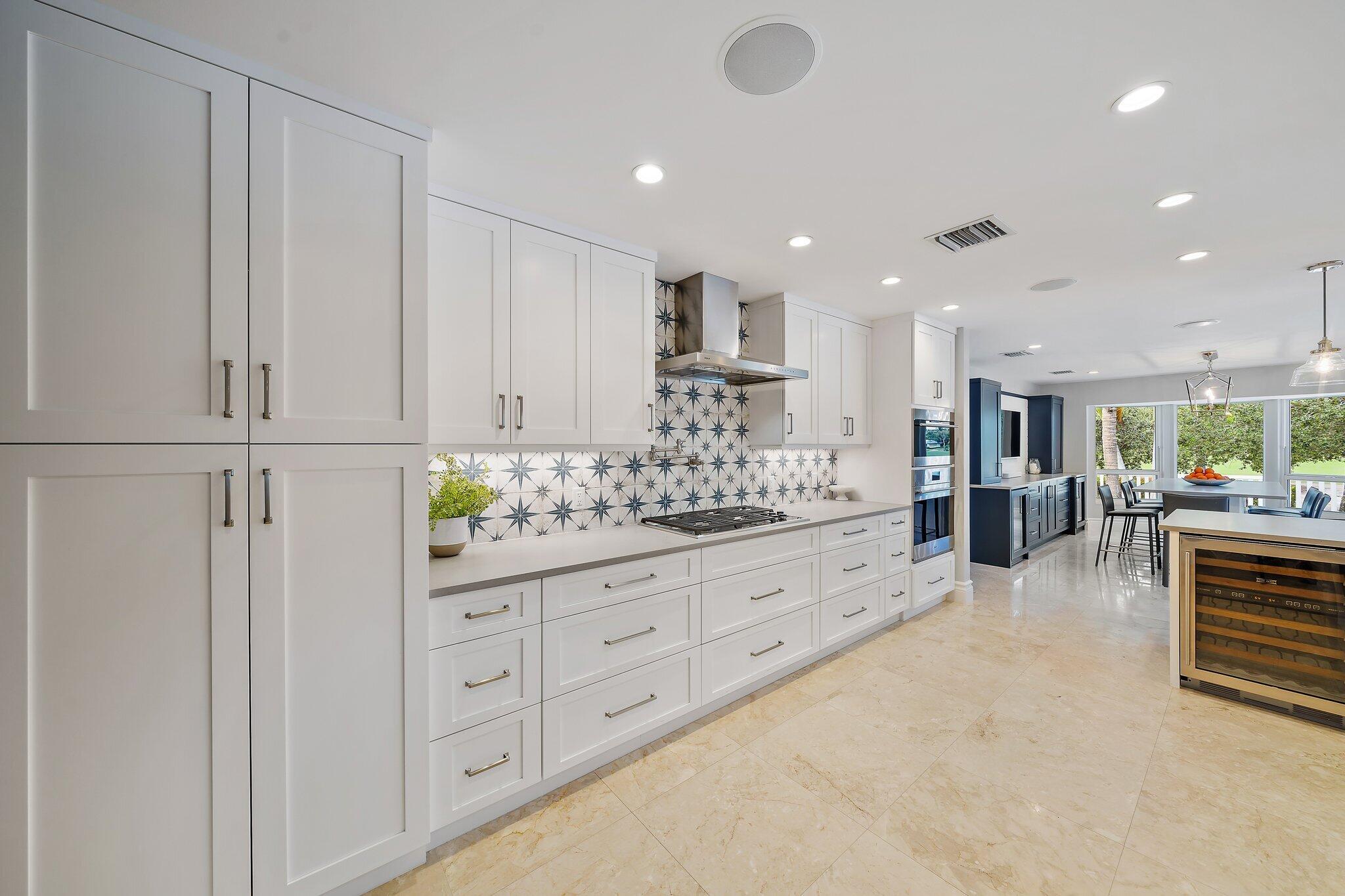 98 Golfview Drive Tequesta, FL 33469 - Photo 6 of 34 a large white kitchen with kitchen island a sink stainless steel appliances and cabinets