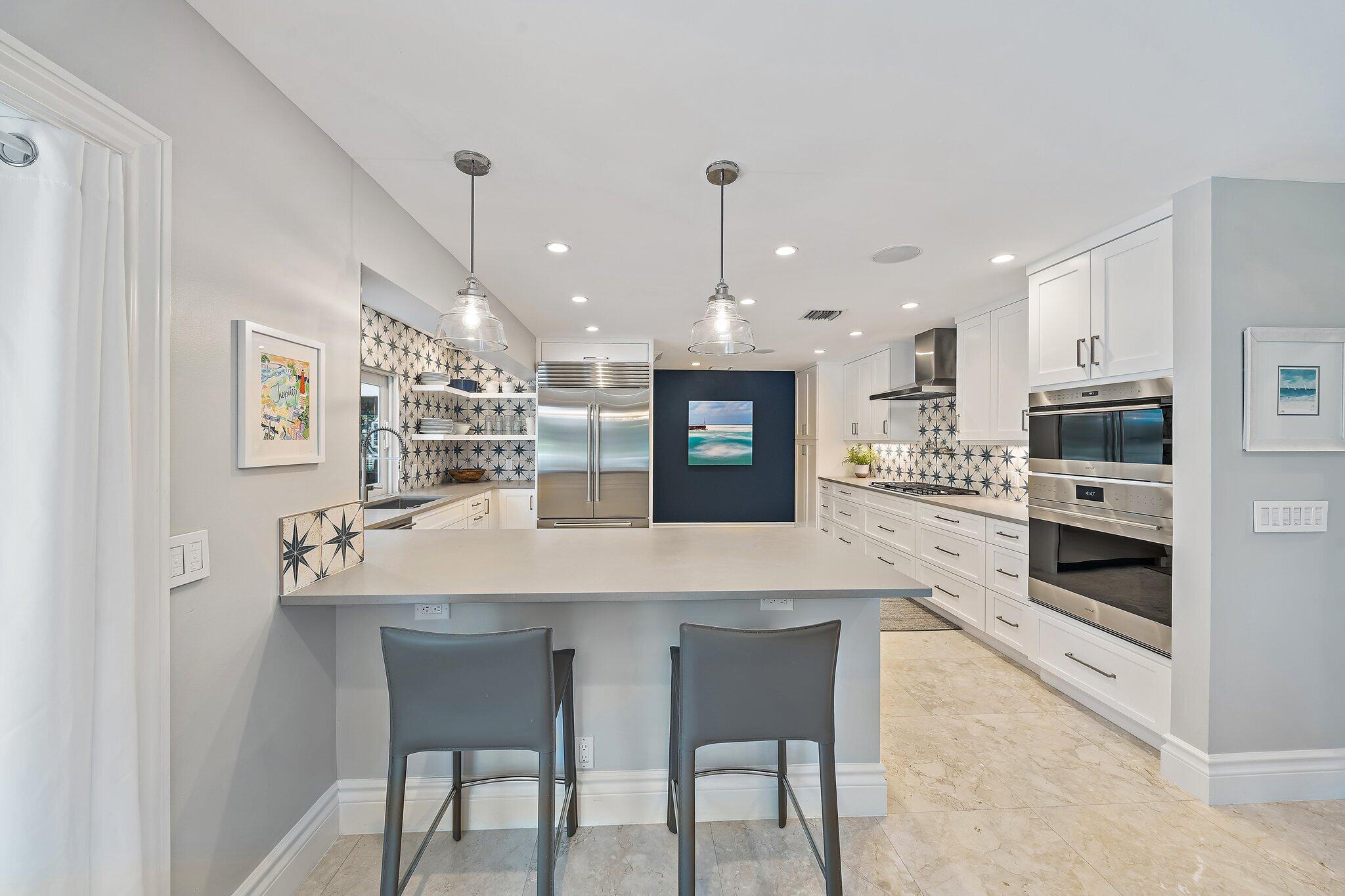 98 Golfview Drive Tequesta, FL 33469 - Photo 8 of 34 a kitchen with stainless steel appliances kitchen island granite countertop a table chairs and a refrigerator