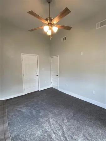 a view of an empty room with a chandelier fan
