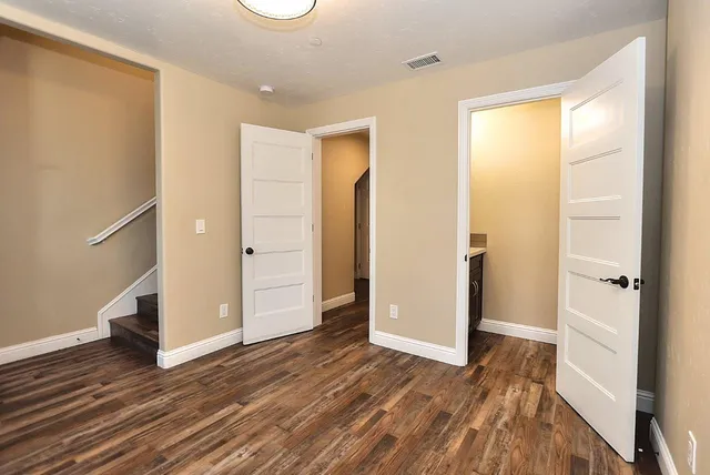 an empty room with wooden floor a ceiling fan and windows