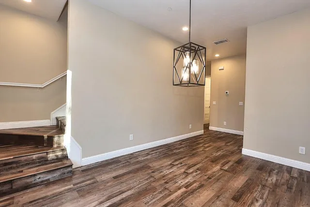an empty room with wooden floor cabinet and windows