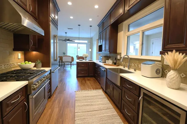 a large kitchen with stainless steel appliances granite countertop a stove a sink dishwasher and cabinets with wooden floor