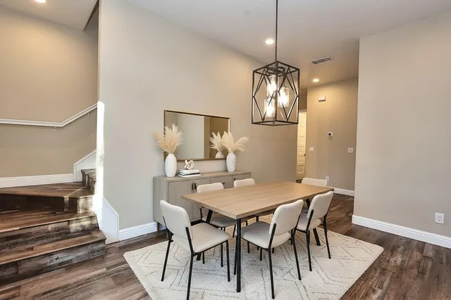 a dining room with wooden floor a chandelier a wooden table and chairs