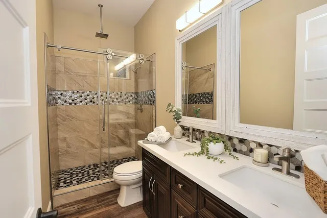 a bathroom with a sink toilet double vanity and shower