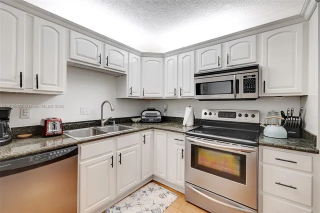 a kitchen with granite countertop a refrigerator stove and microwave
