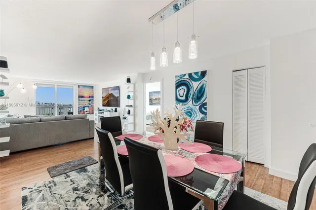 a dining room with wooden floor a chandelier a wooden table and chairs
