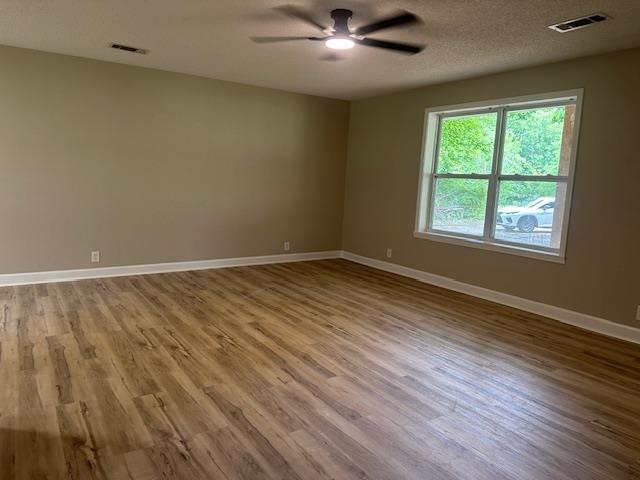 15 Brookwood Loop Adamsville, TN 38310 - Photo 6 of 21 an empty room with wooden floor chandelier fan and windows