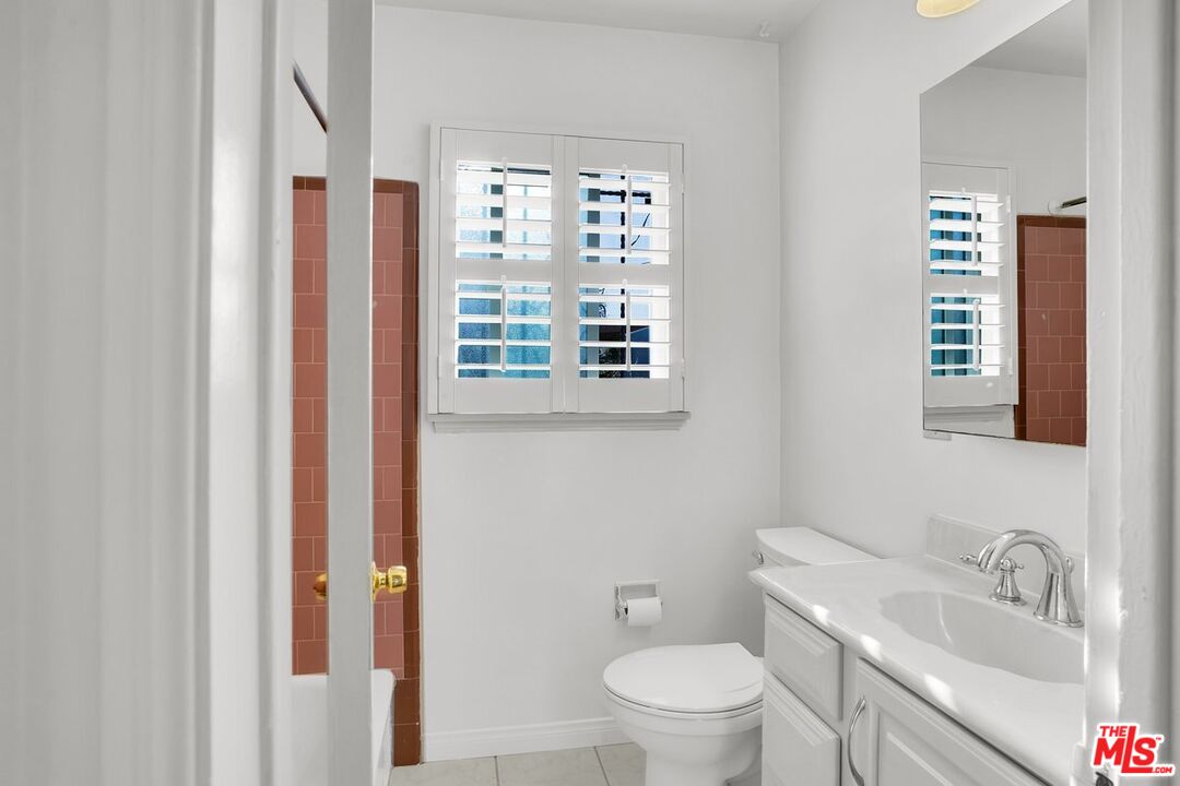 1316 South Castlegate Avenue Compton, CA 90221 - Photo 14 of 28 a bathroom with a granite countertop toilet a sink and a mirror