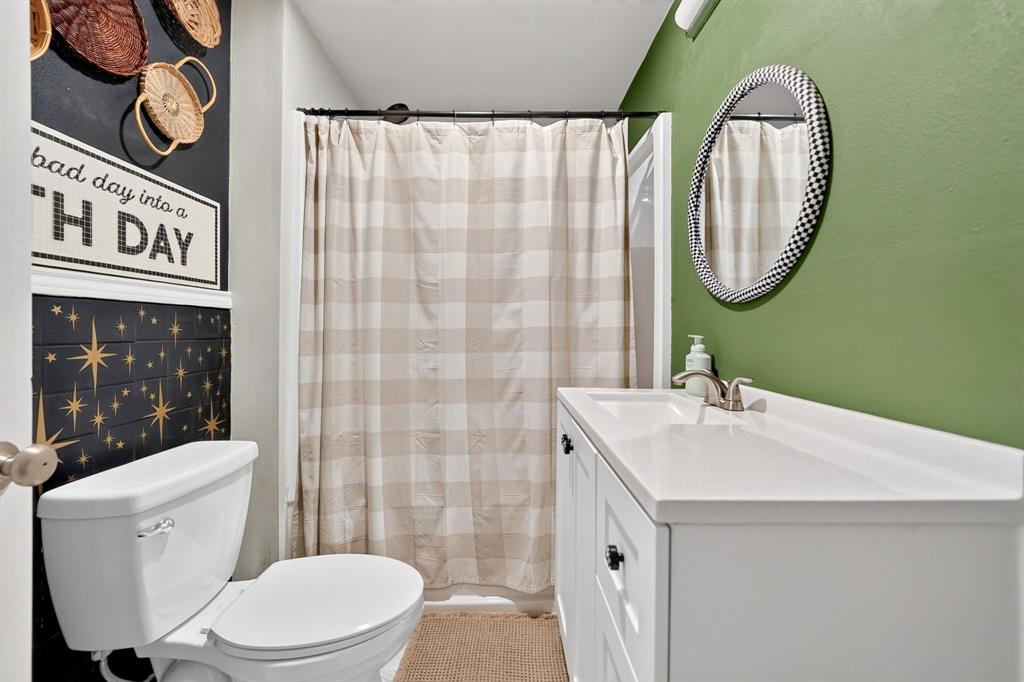 810 Edna Street Athens, TX 75751 - Photo 24 of 28 Bathroom featuring a white single-basin vanity with integrated countertop, a circular mirror, and a commode