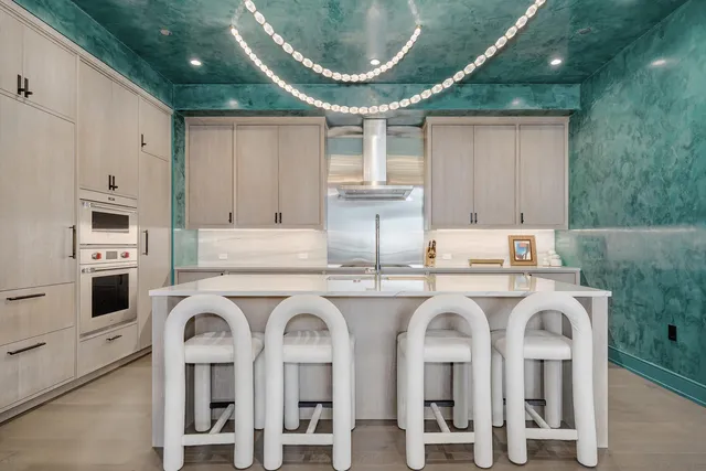 a white kitchen with stainless steel appliances granite countertop a stove a sink and a refrigerator