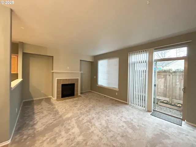 a view of an empty room with a fireplace and a window