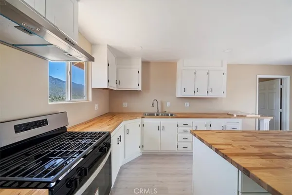 a large kitchen with kitchen island a sink dishwasher stove and white cabinets with wooden floor