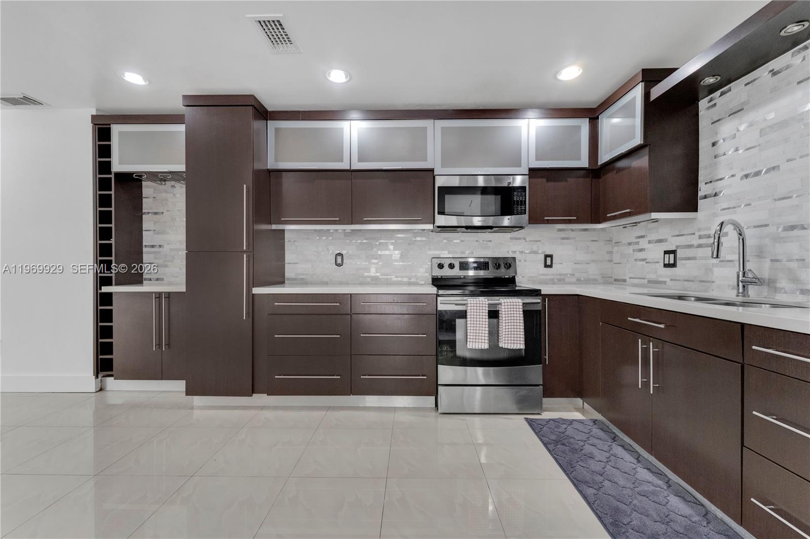 9646 Southwest 151st Avenue, Unit 1 Miami, FL 33196 - Photo 9 of 26 a kitchen with stainless steel appliances kitchen island granite countertop a stove and a sink