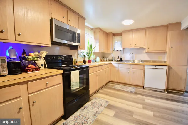 a living room with stainless steel appliances furniture a rug and a kitchen view