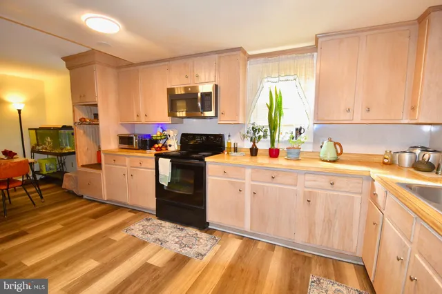 a kitchen with stainless steel appliances granite countertop a stove top oven a sink dishwasher and white cabinets with wooden floor