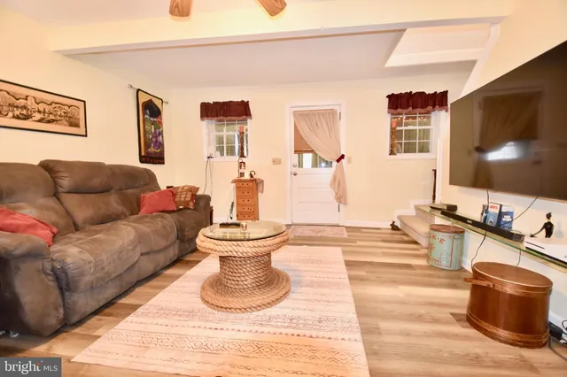 a living room with furniture a chandelier and a dining table with wooden floor