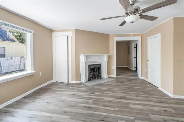 a view of a livingroom with a fireplace a ceiling fan and wooden floor