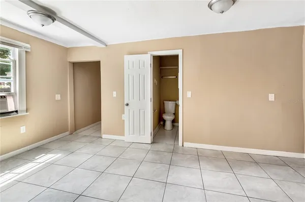 a view of an empty room with closet and a window