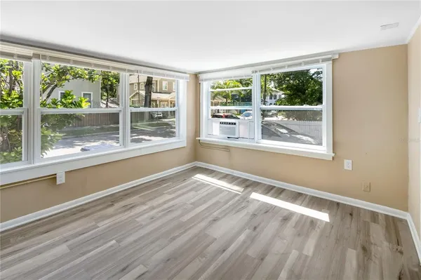 a view of an empty room with wooden floor and a window