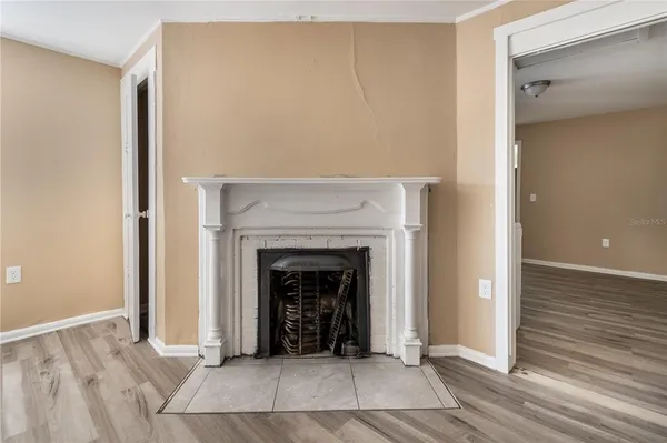 a view of an empty room with wooden floor and a fireplace
