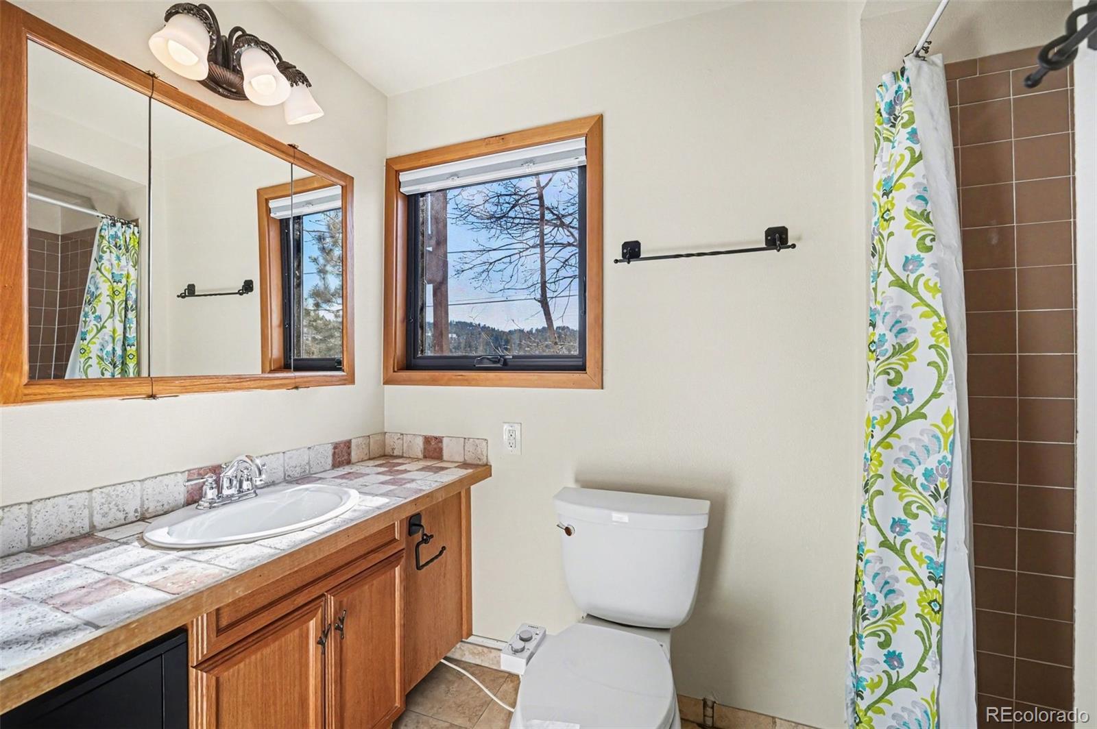 3260 Bit Road Evergreen, CO 80439 - Photo 19 of 26 a bathroom with a granite countertop sink and a mirror
