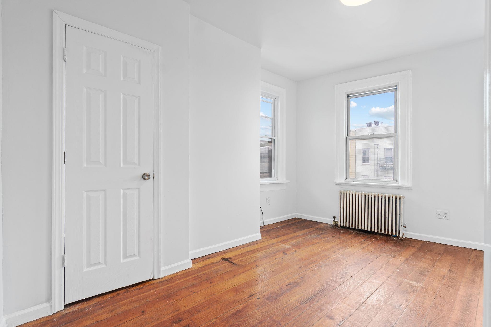 91 Ocean Avenue, Unit 3 Jersey City, NJ 07305 - Photo 6 of 14 an empty room with wooden floor and windows