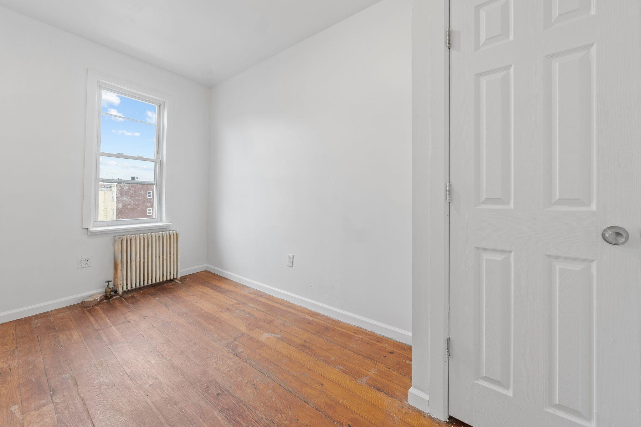 91 Ocean Avenue, Unit 3 Jersey City, NJ 07305 - Photo 8 of 14 an empty room with wooden floor and windows