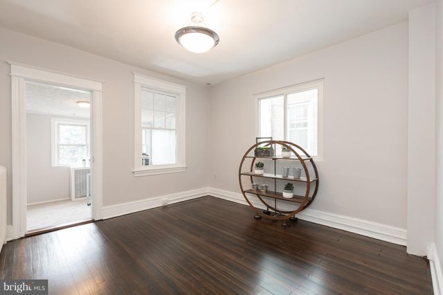an empty room with wooden floor mirror and window