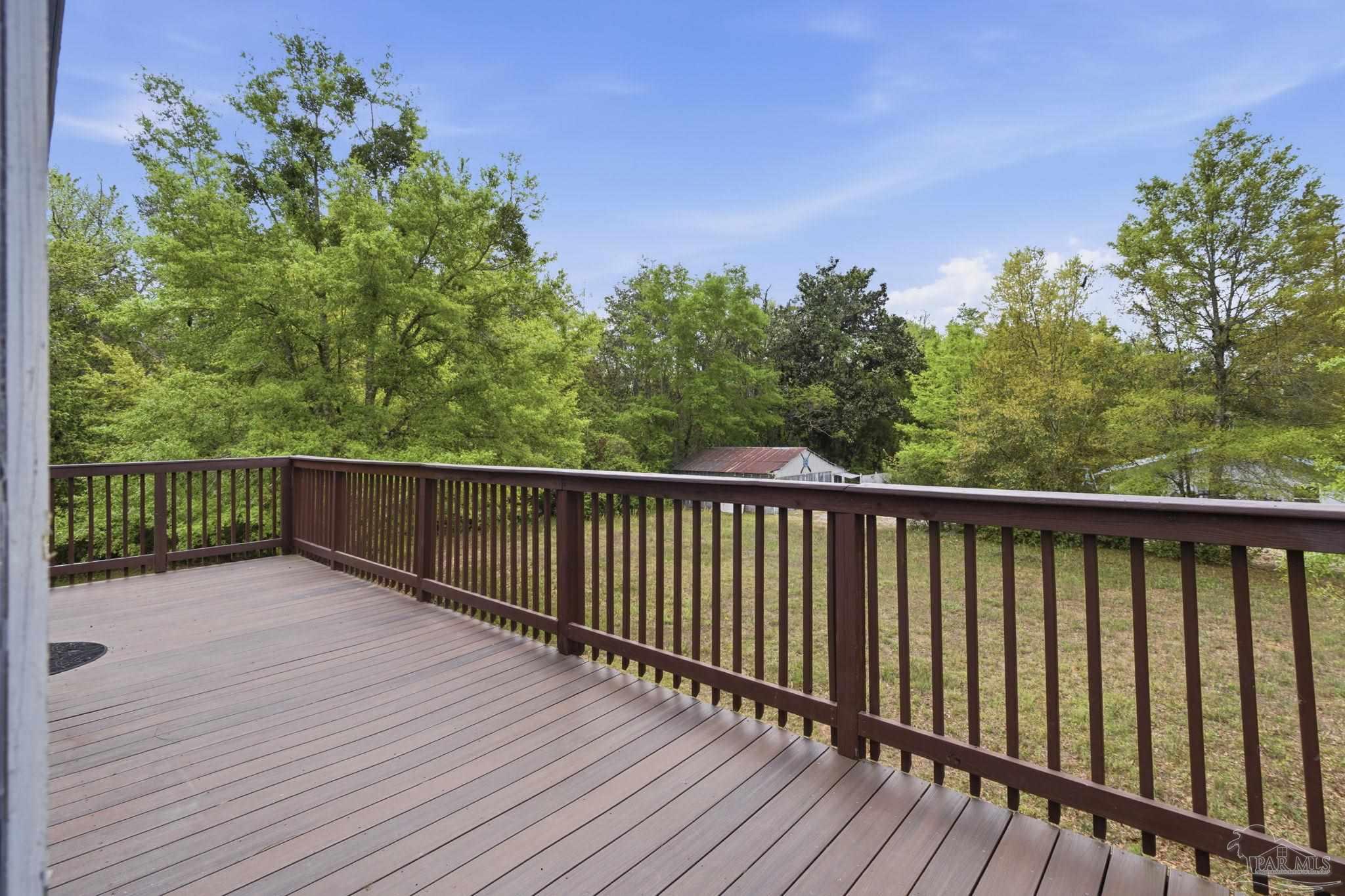 4032 Mae Lane Milton, FL 32583 - Photo 13 of 50 a balcony with wooden floor and trees in the background