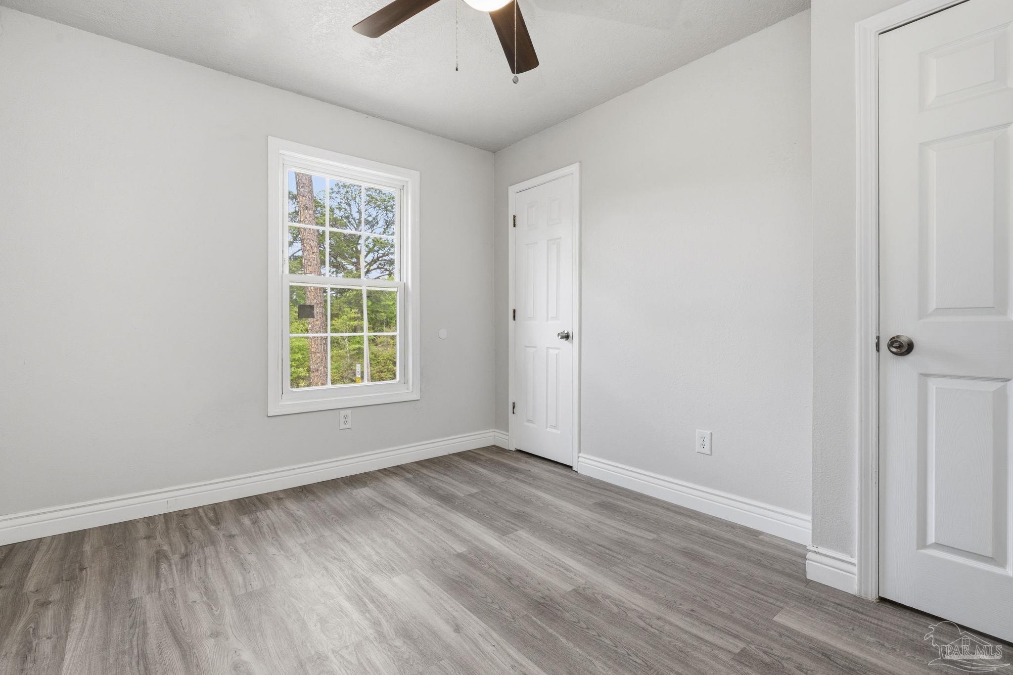 4032 Mae Lane Milton, FL 32583 - Photo 24 of 50 an empty room with wooden floor cabinet and windows