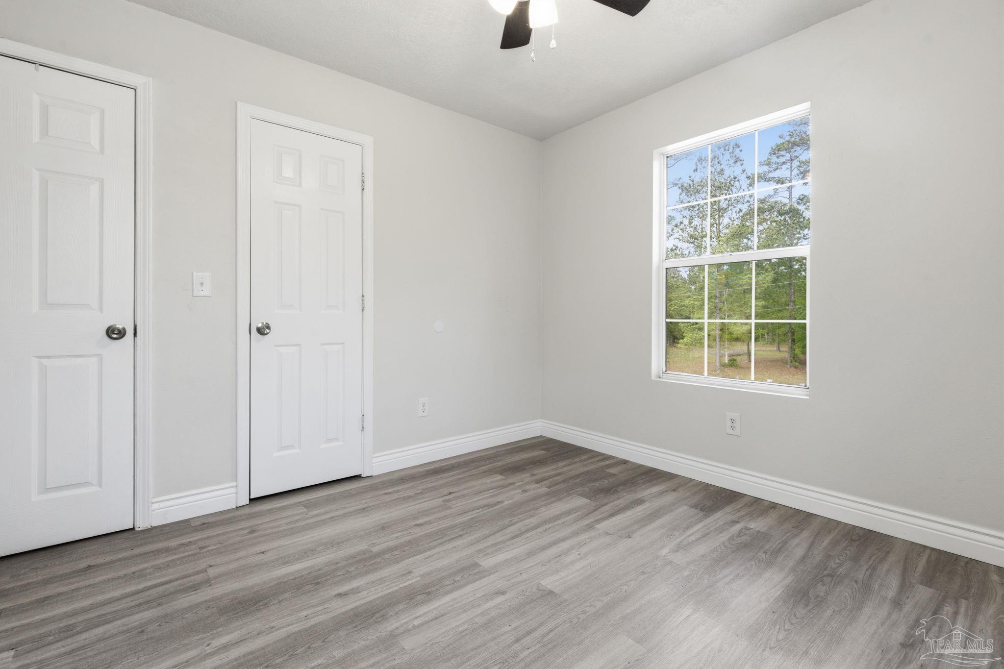 4032 Mae Lane Milton, FL 32583 - Photo 26 of 50 a view of an empty room with wooden floor and a window