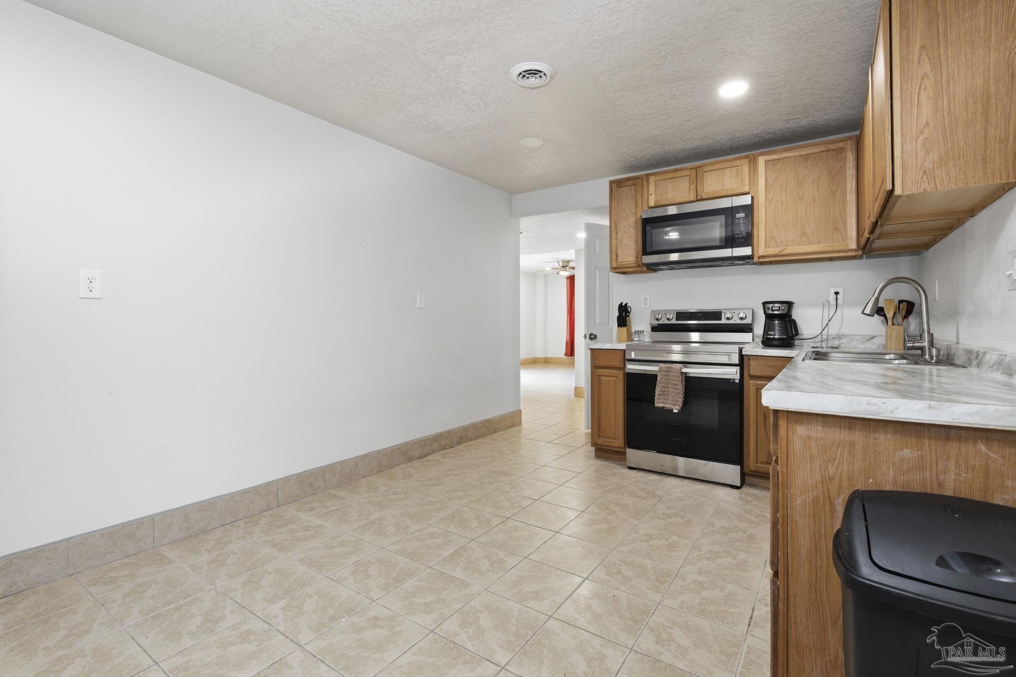 4032 Mae Lane Milton, FL 32583 - Photo 30 of 50 a kitchen with stainless steel appliances a stove a sink a microwave and cabinets