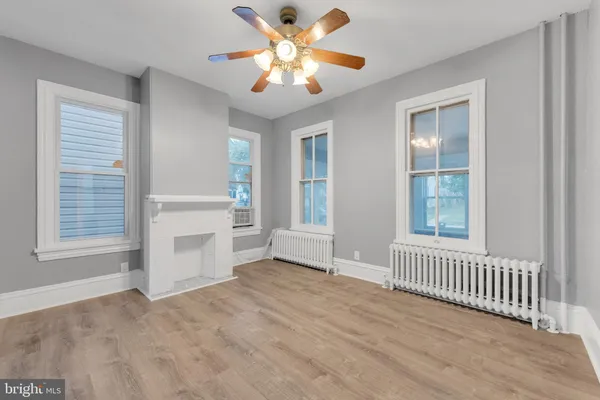an empty room with chandelier fan and windows